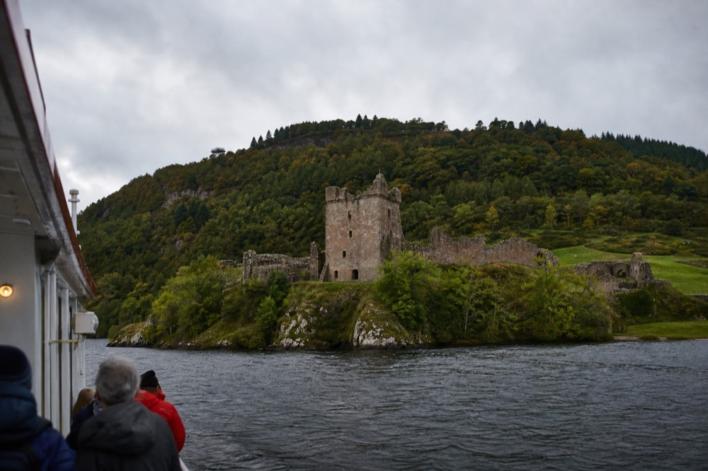 Cruise passengers looking up at Urquhart Castle from a boat on Loch Ness