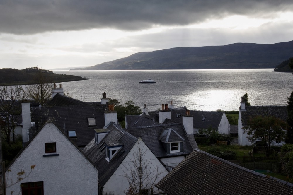 A Highland village on the shore of Loch Ness with the dark water and wooded hills of the Great Glen behind it