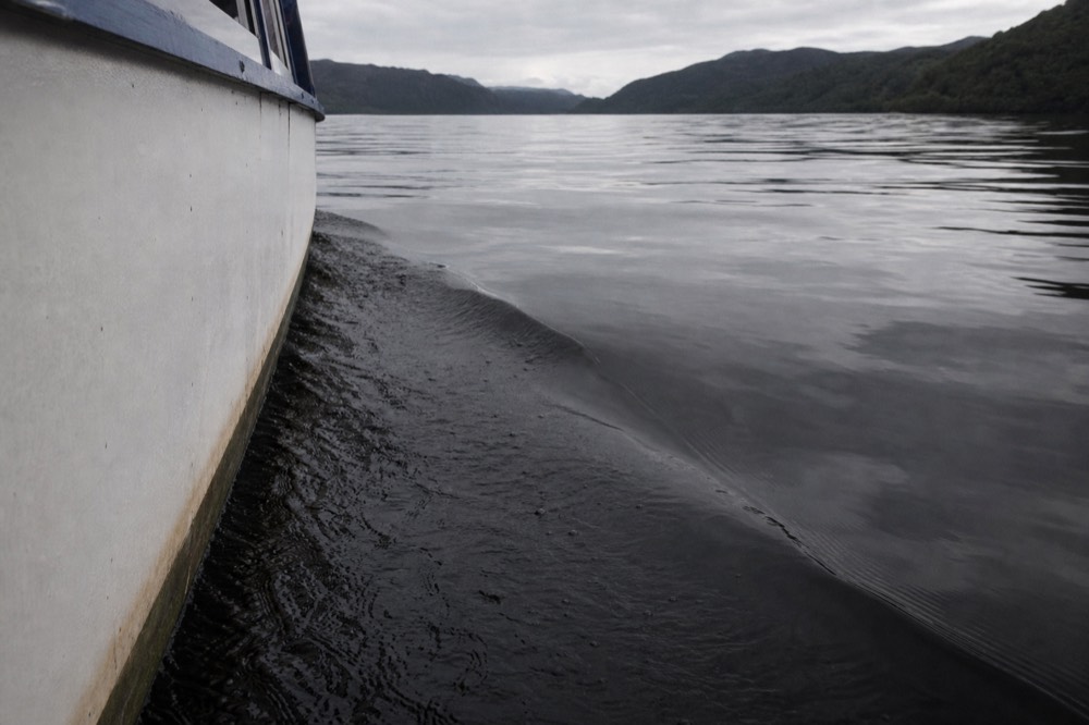A close study of the near-black peaty surface of Loch Ness, dark water with faint hill reflections